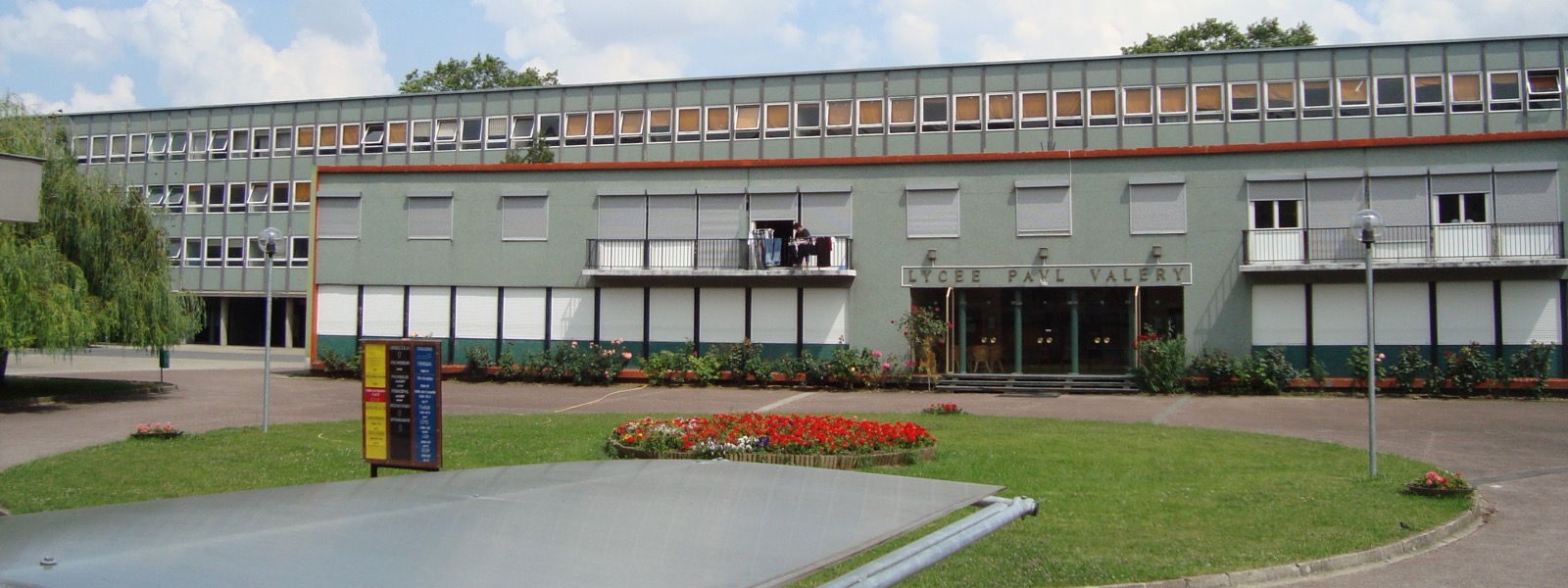 Façade du lycée Paul-Valéry, bâtiment des années soixante aux stores blancs, derrière une pelouse fleurie