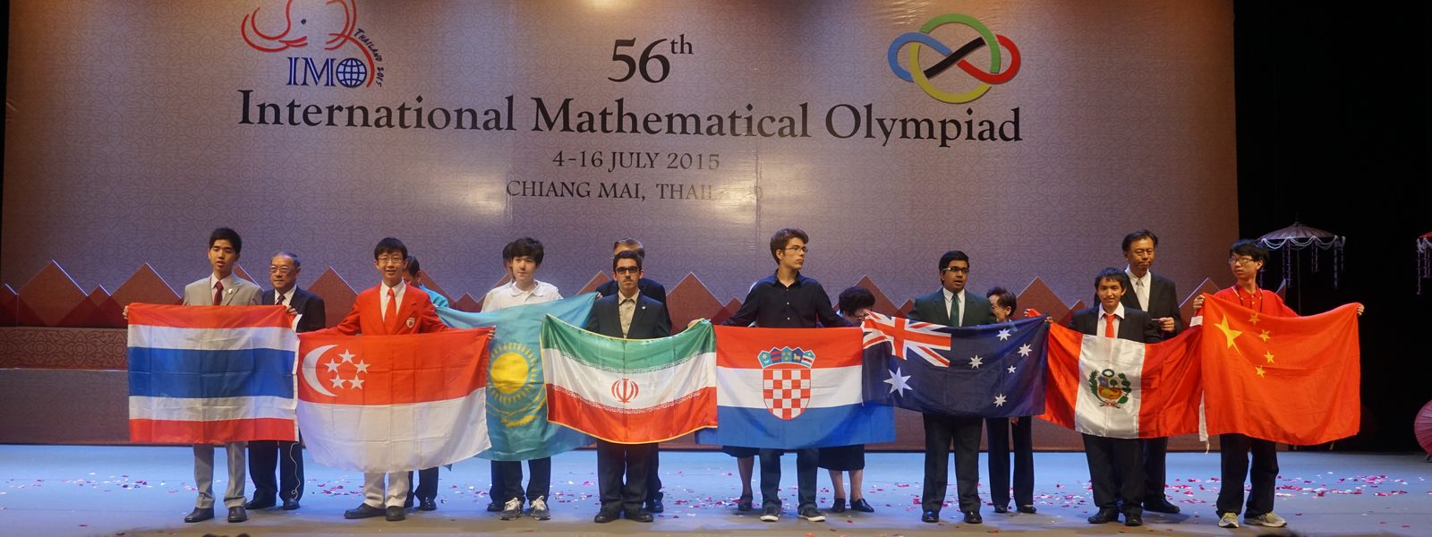 Des élèves de plusieurs pays tiennent leur drapeau sur la scène de la cérémonie de clôture de l'Olympiade internationale de mathématiques 2015